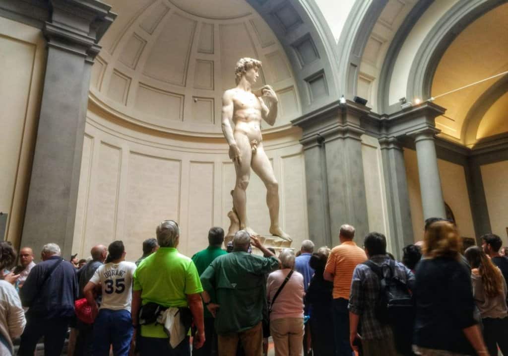 Full view of Michelangelo's David with large crowd around the base.