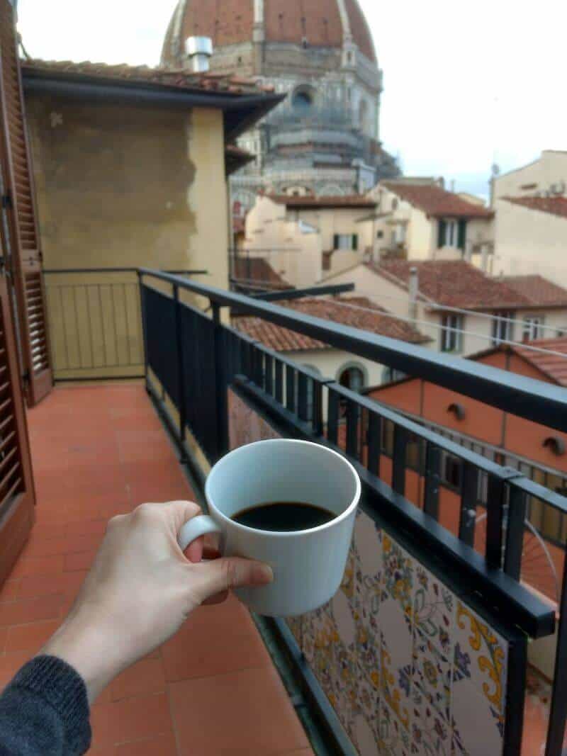 Cup of coffee on a balcony in Florence, Italy, with the Duomo dome in the distance.