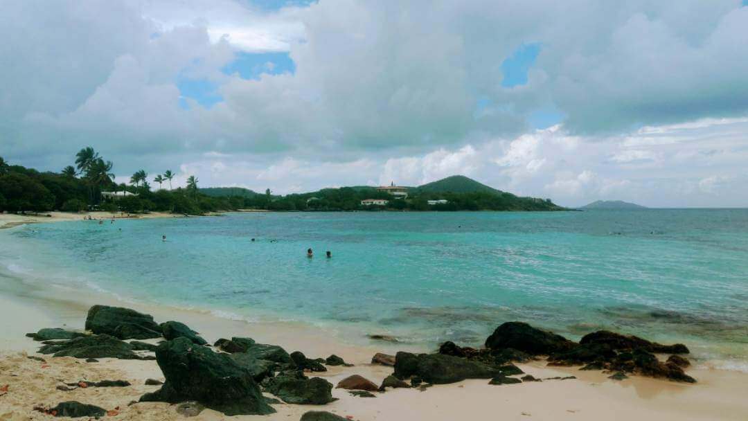 Rocks and sand on a beach with clear turquoise water on St. Thomas in the Virgin Islands.