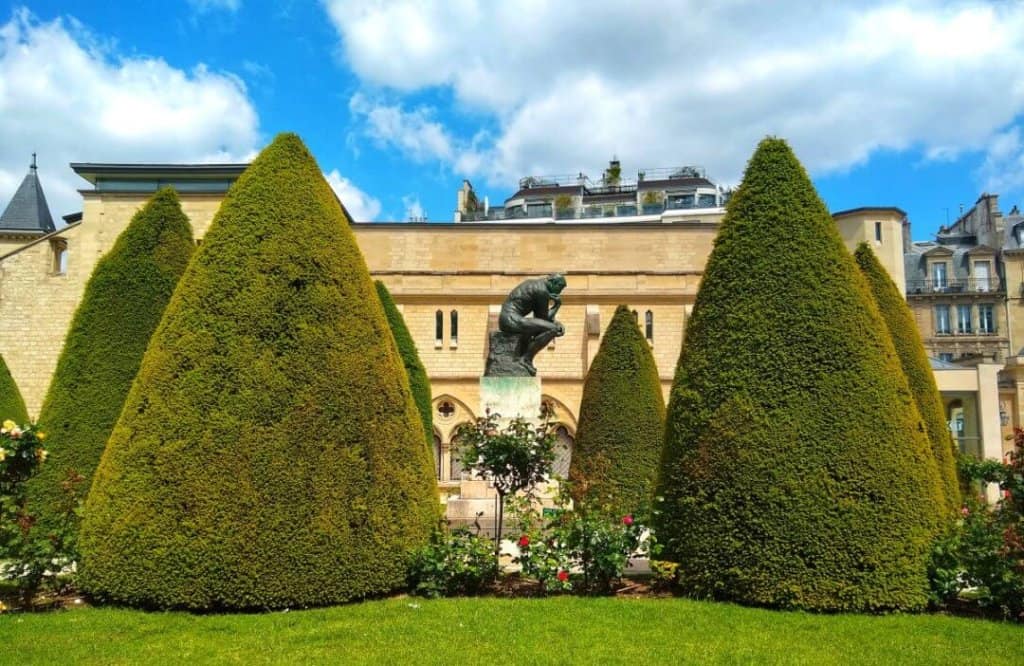 Rodin's Thinker sculpture in the middle of trimmed hedges in the artist's garden in Paris.