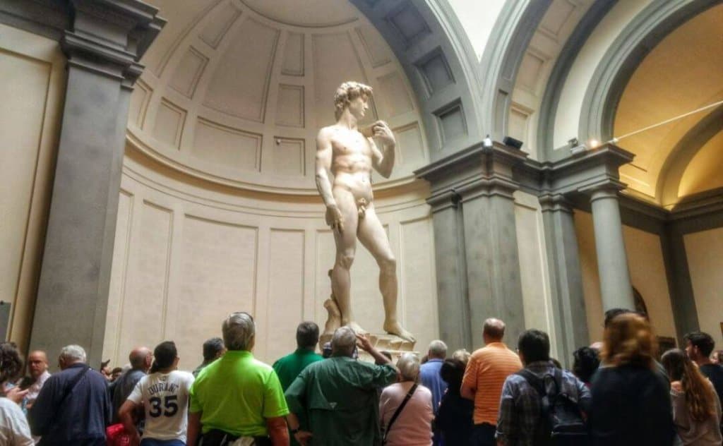 Michelangelo's David with a crowd gathered on display at Galleria dell'Accademia in Florence, Italy