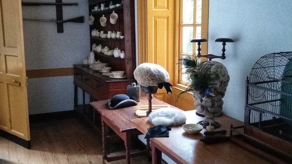 18th Century wigs on stands in a room in a colonial house.