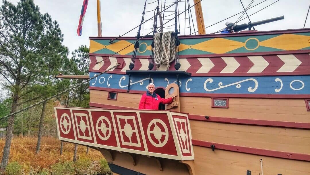 Man with grey hair standing near the edge of a replica 17th century ship.