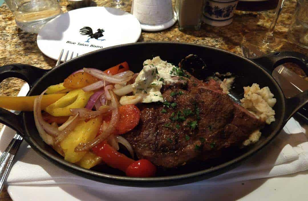 Braised lamb shank in a cast iron skillet on a bed of mashed potatoes with vegetables