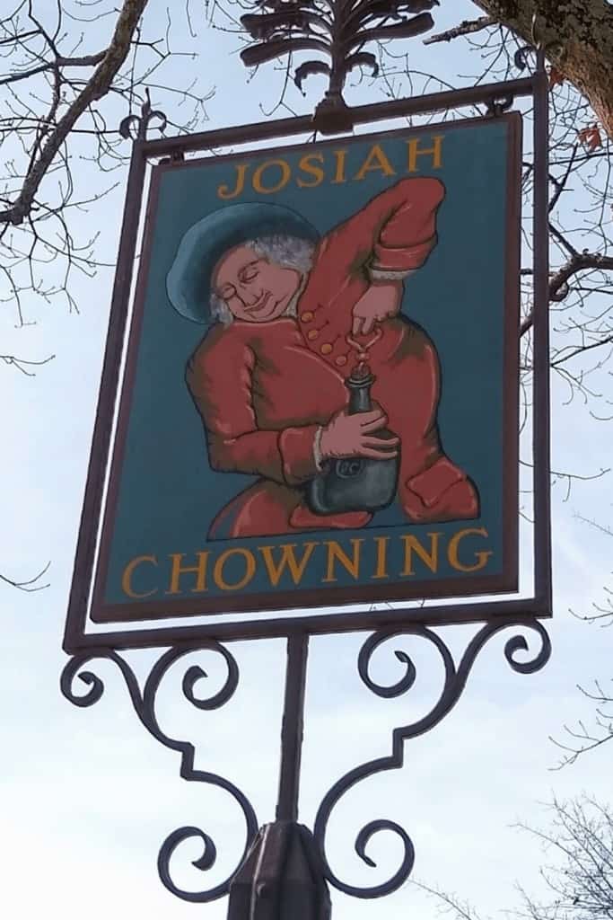 Wrought iron frame around a painted sign of a man opening a jug that says Josiah Chowning