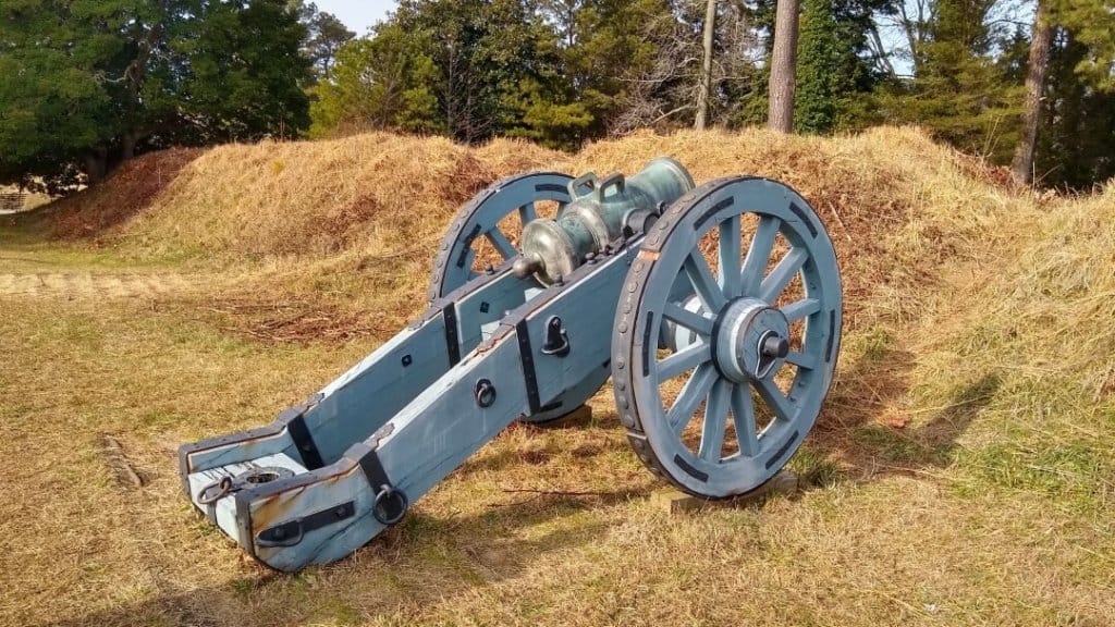 Old American Revolution canon sitting behind embankment on a battlefield.
