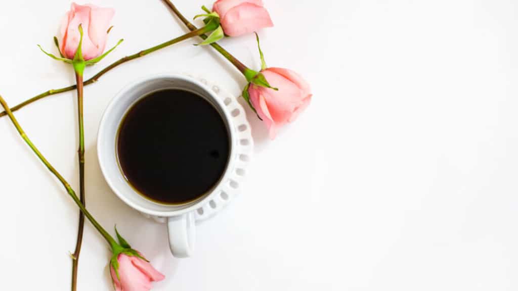 White cup of coffee on a white background with pink roses