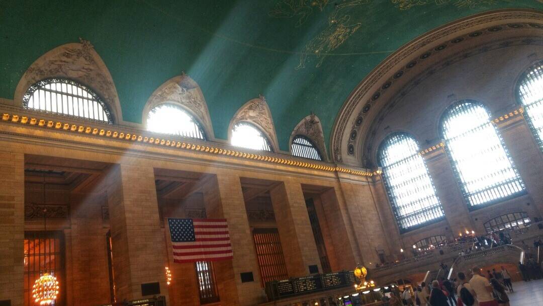 Inside the Grand Central Terminal main hall with sun streaming in through the large windows.