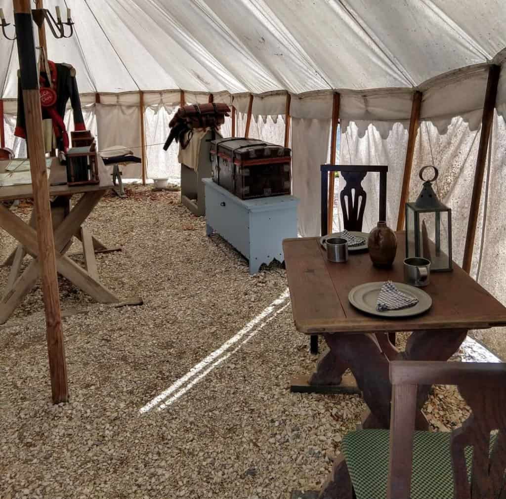 Interior of a revolutionary war military tent full of equipment and furnishings.