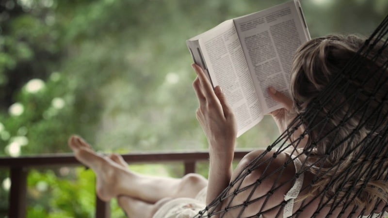 Woman in a hammock reading a book.