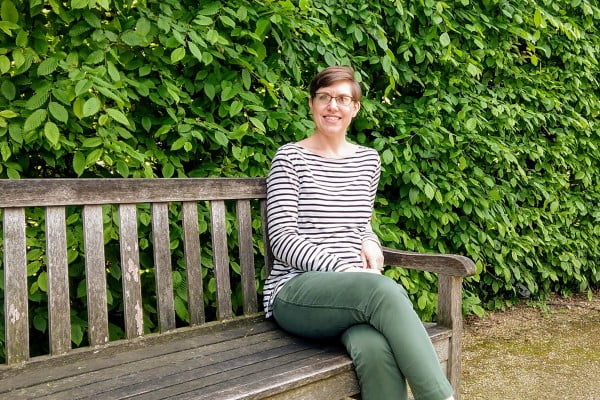 woman sitting on a wooden bench in a garden