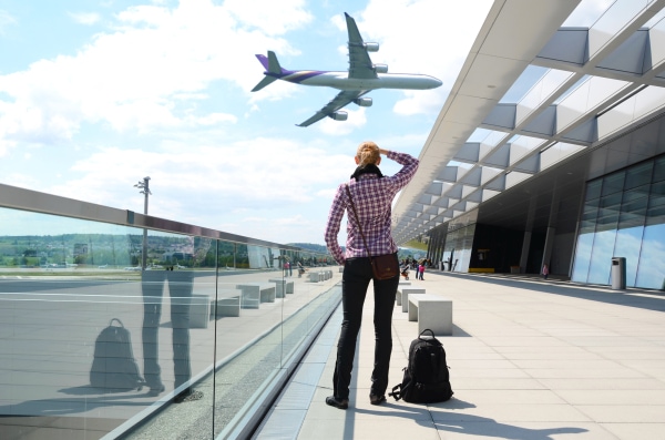 Girl in the airport with a carry-on bag packed for a long flight