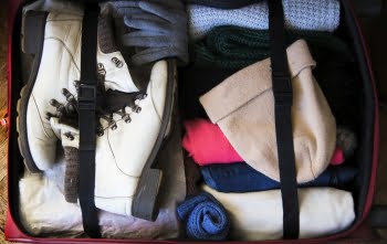 Winter weather clothing in an open suitcase packed for a weekend away