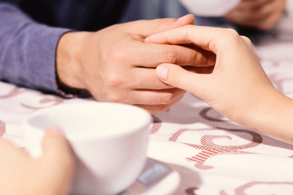 Couple holding hands while enjoying coffee