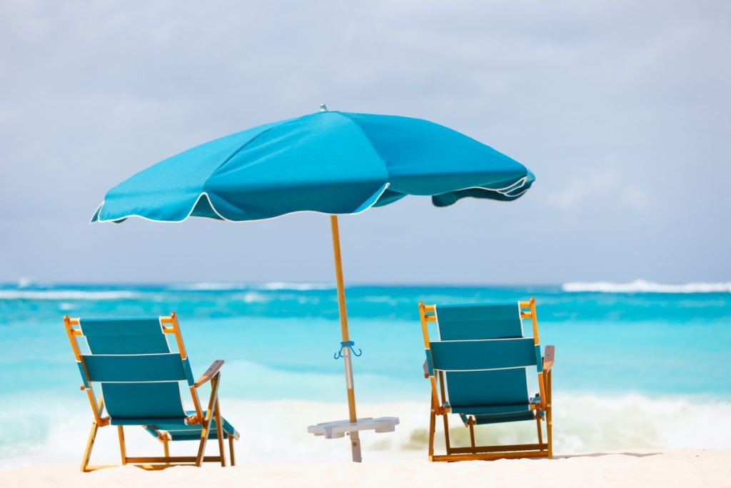 Umbrella and a beach chair on a sandy beach at the shore