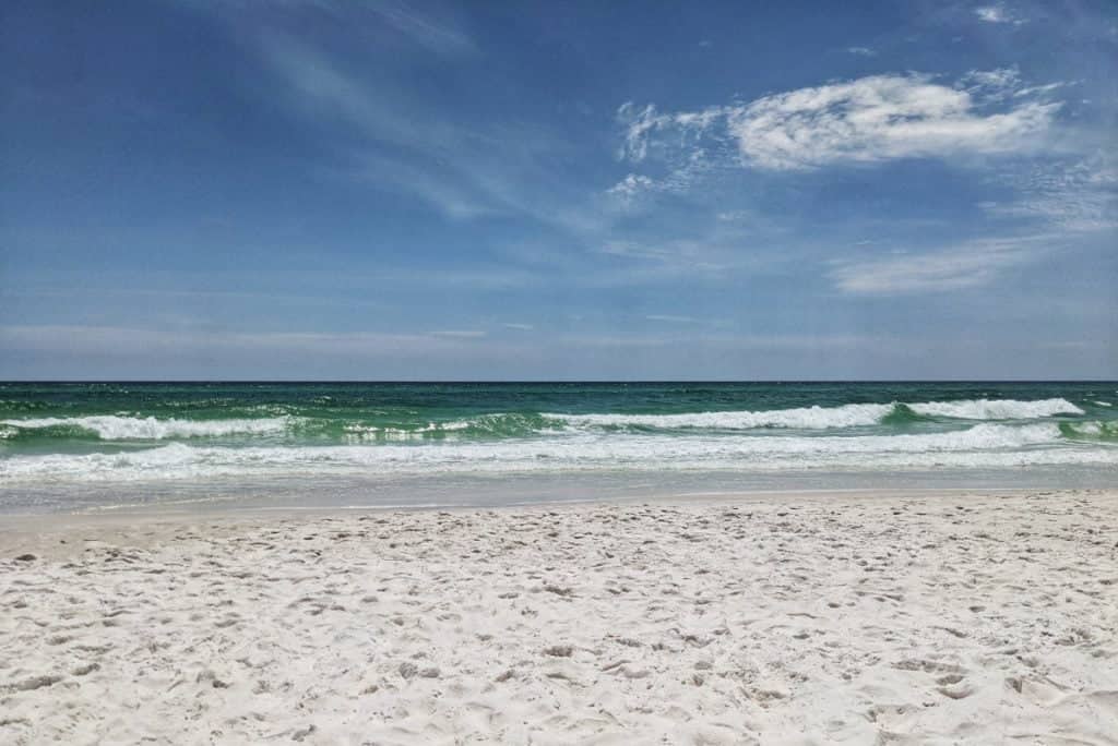 blue green waves crashing on a white sandy beach along 30A in Florida
