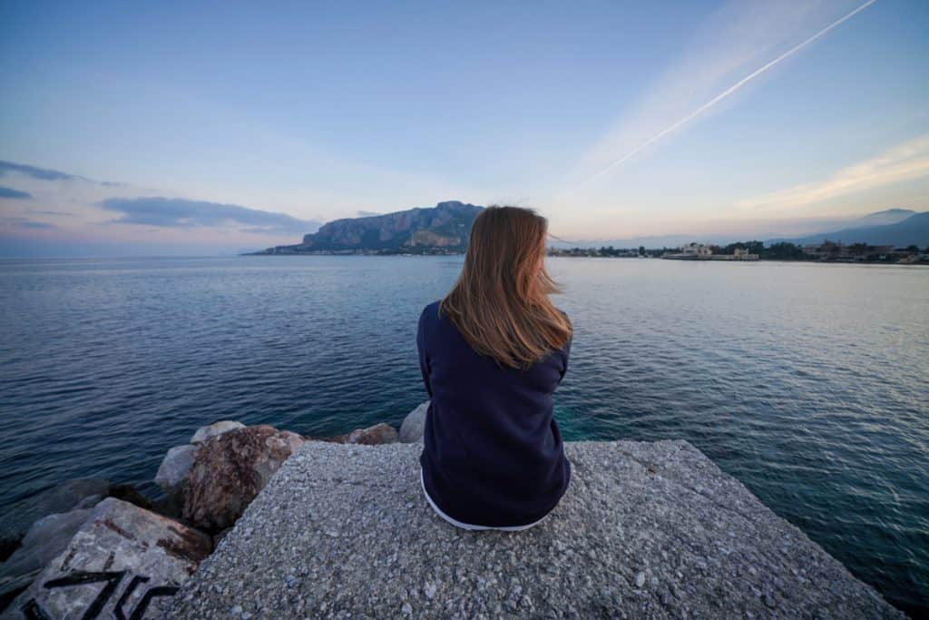 Traveling woman sitting on the edge of the water.