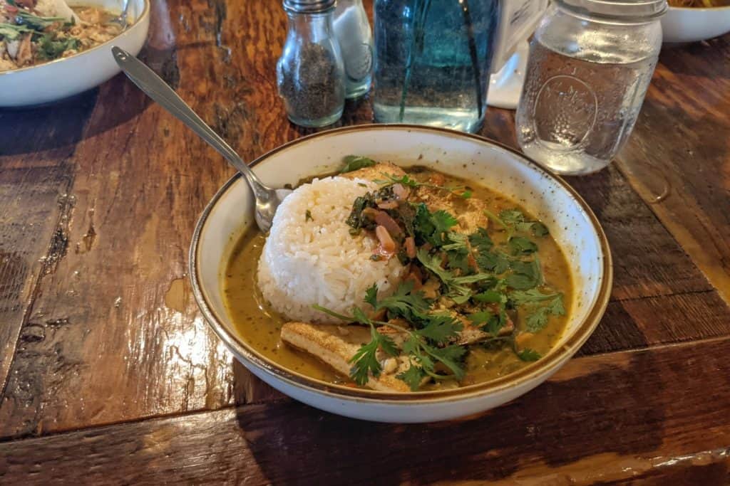 Large white bowl willed with golden curry and rice on a wooden table