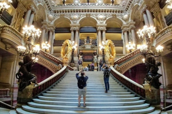 people take photos on the grand staircase in the Paris Opera House
