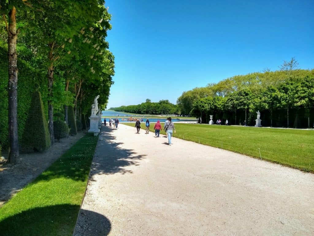 People walking along a path in the gardens of Versailles