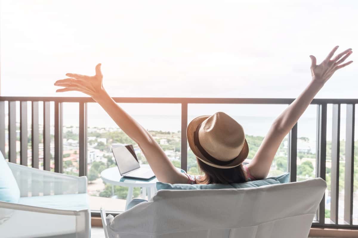 Woman sitting on a balcony with arms outstretched