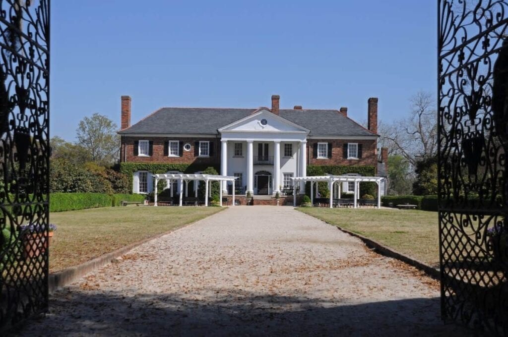 large plantation house beyond a wrought iron gate