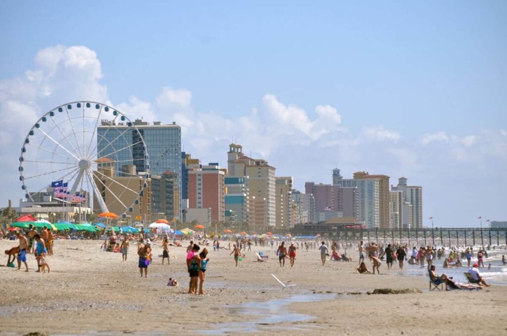 crowds on a beach with tall buildings in the background