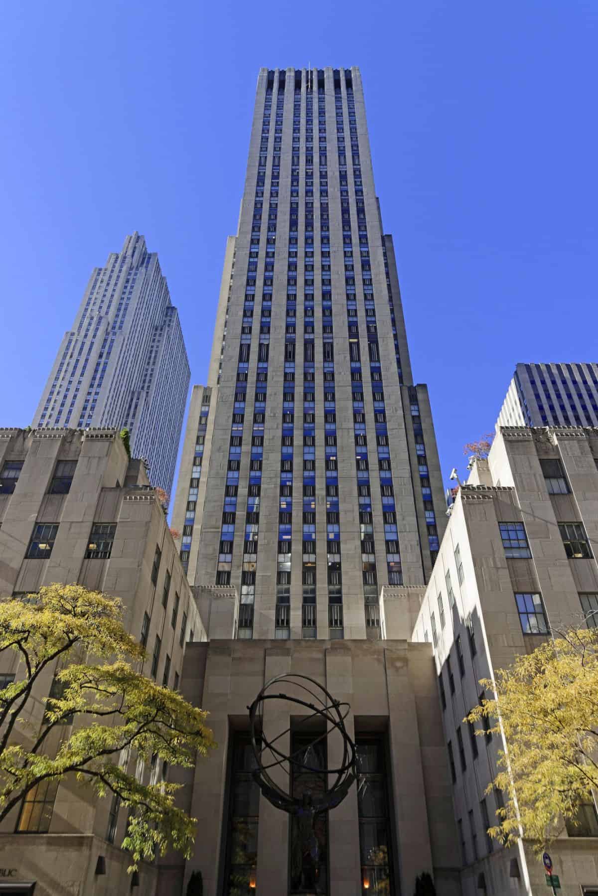 tall building in New York City with a sculpture in front