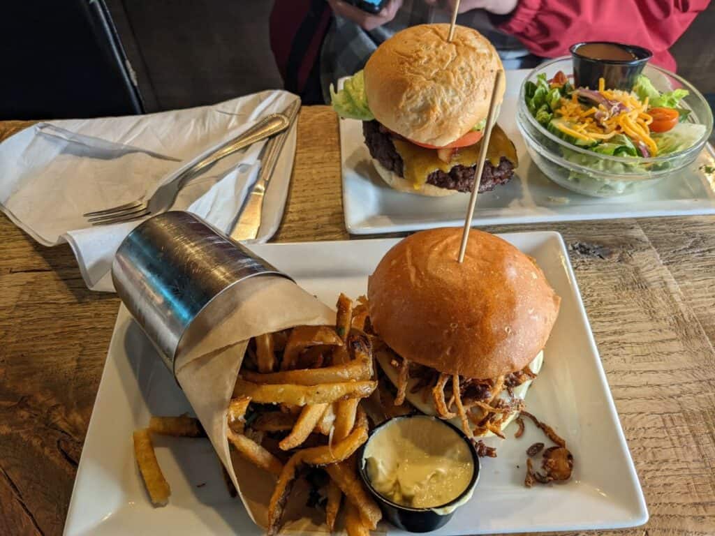Two plates of burgers on a wooden table