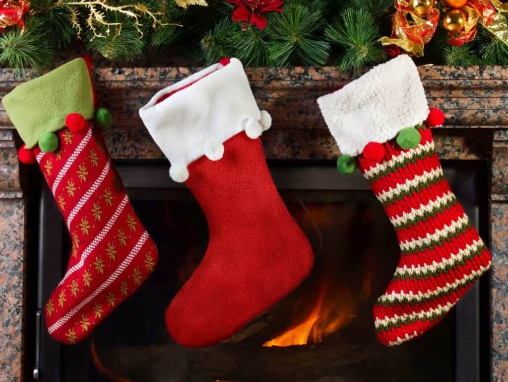 Three Christmas stockings hanging in front of a fire.