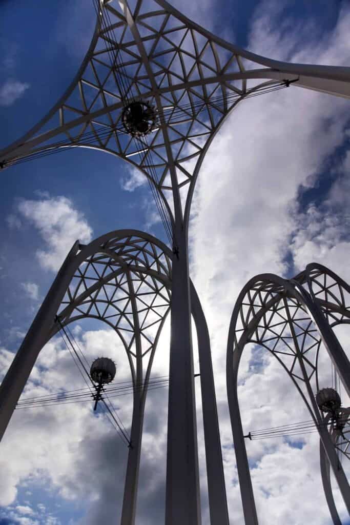tall white steel arches against a blue sky with puffy clouds