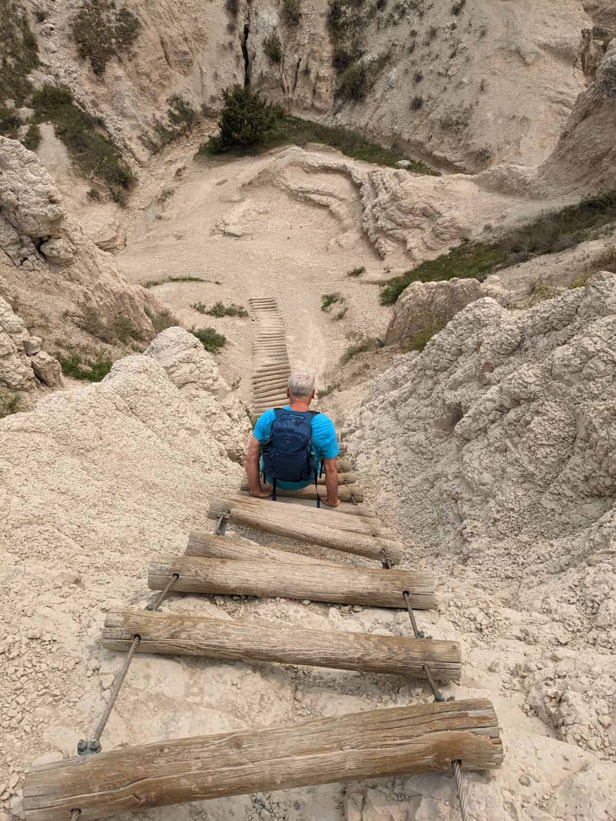 Man climbing down a wooden ladder on Notch Trail in Badlands National Park