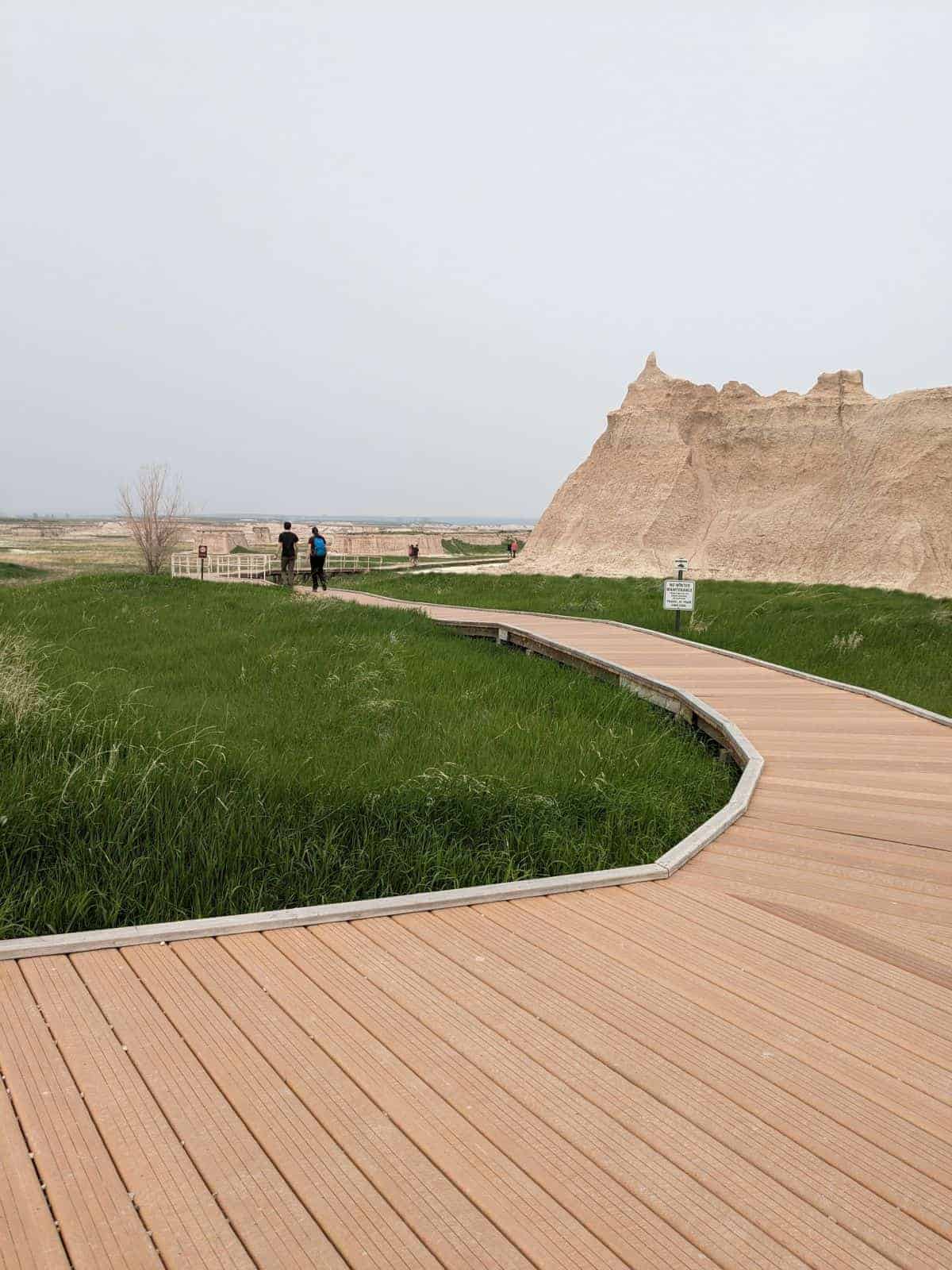 Boardwalk path over prairie grass toward rock formations at Door Trail in Badlands National Park