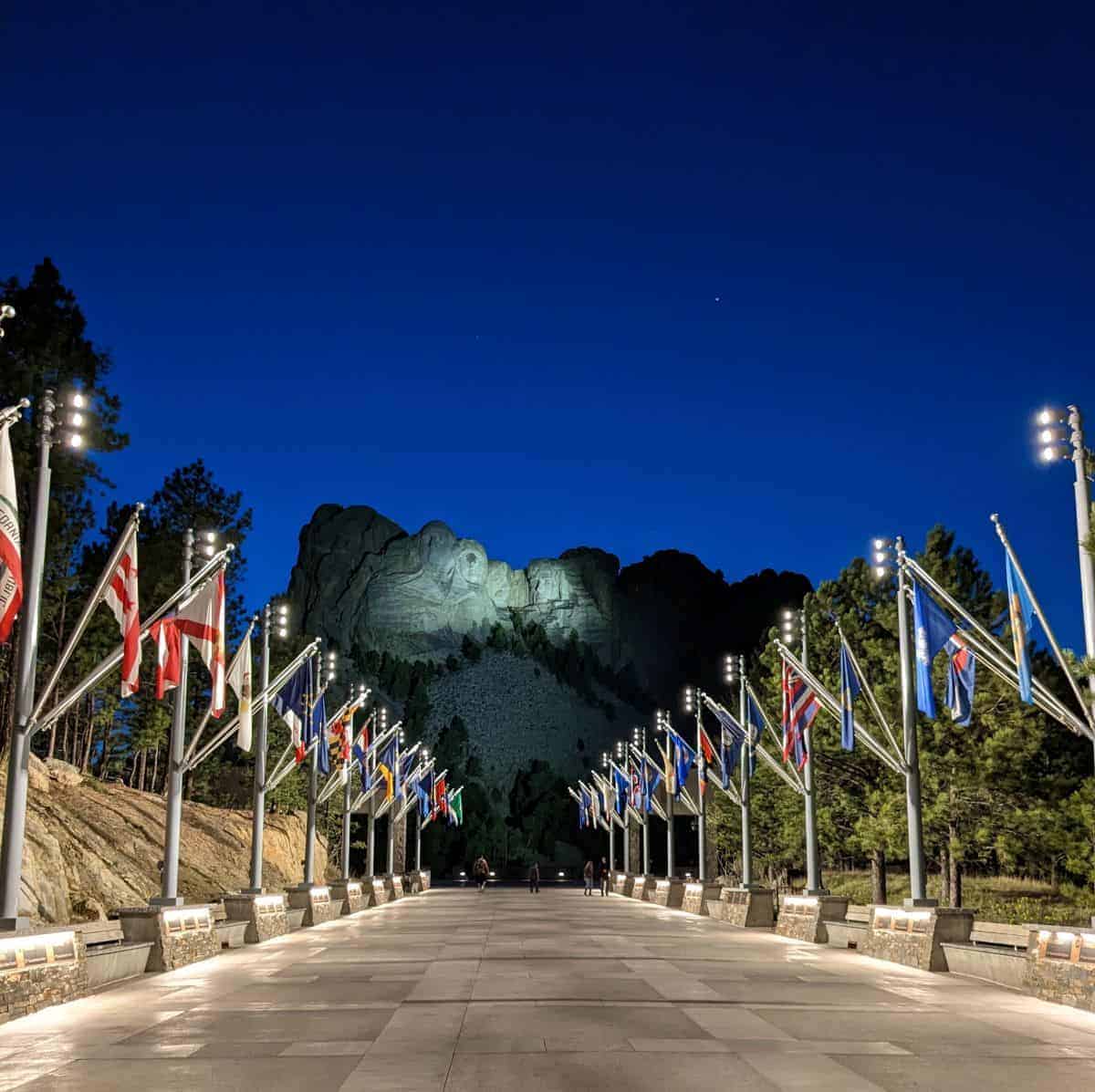 view of Mount Rushmore in the evening down a long walkway flanked by flags