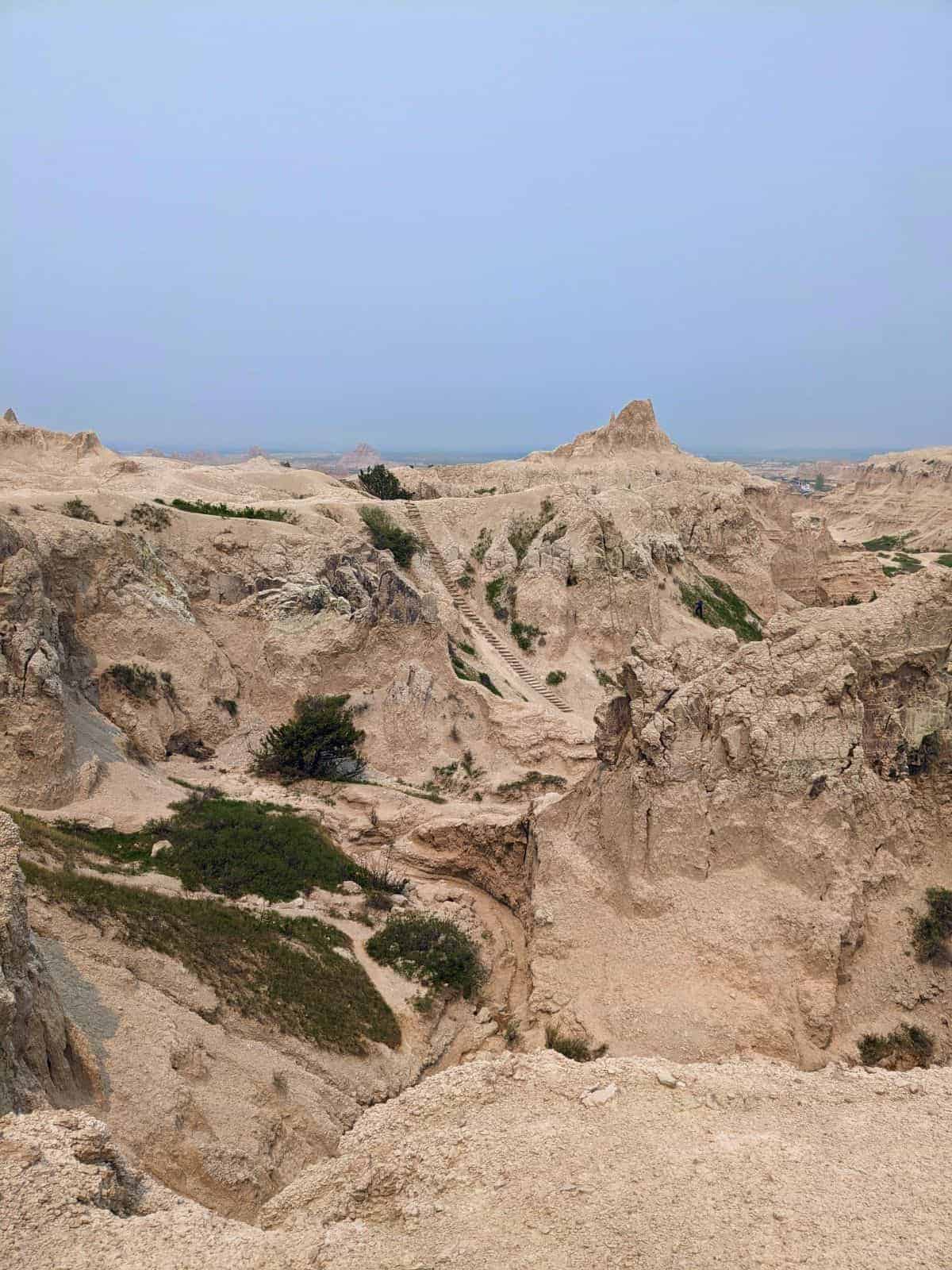 view of rugged rock formations with a tall, steep log ladder reach to the top of the ledge