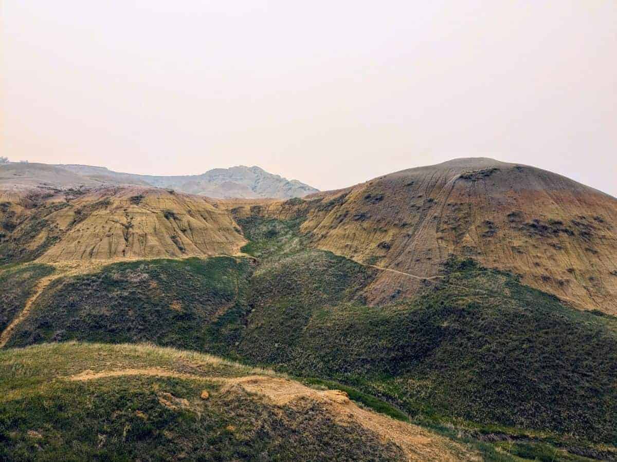 yellow, mounded rock formations with slopes of green grass