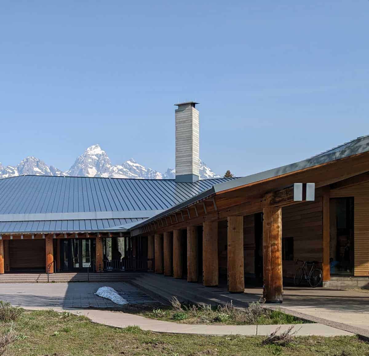 large wood visitor center with wood pillars and mountains in the distance