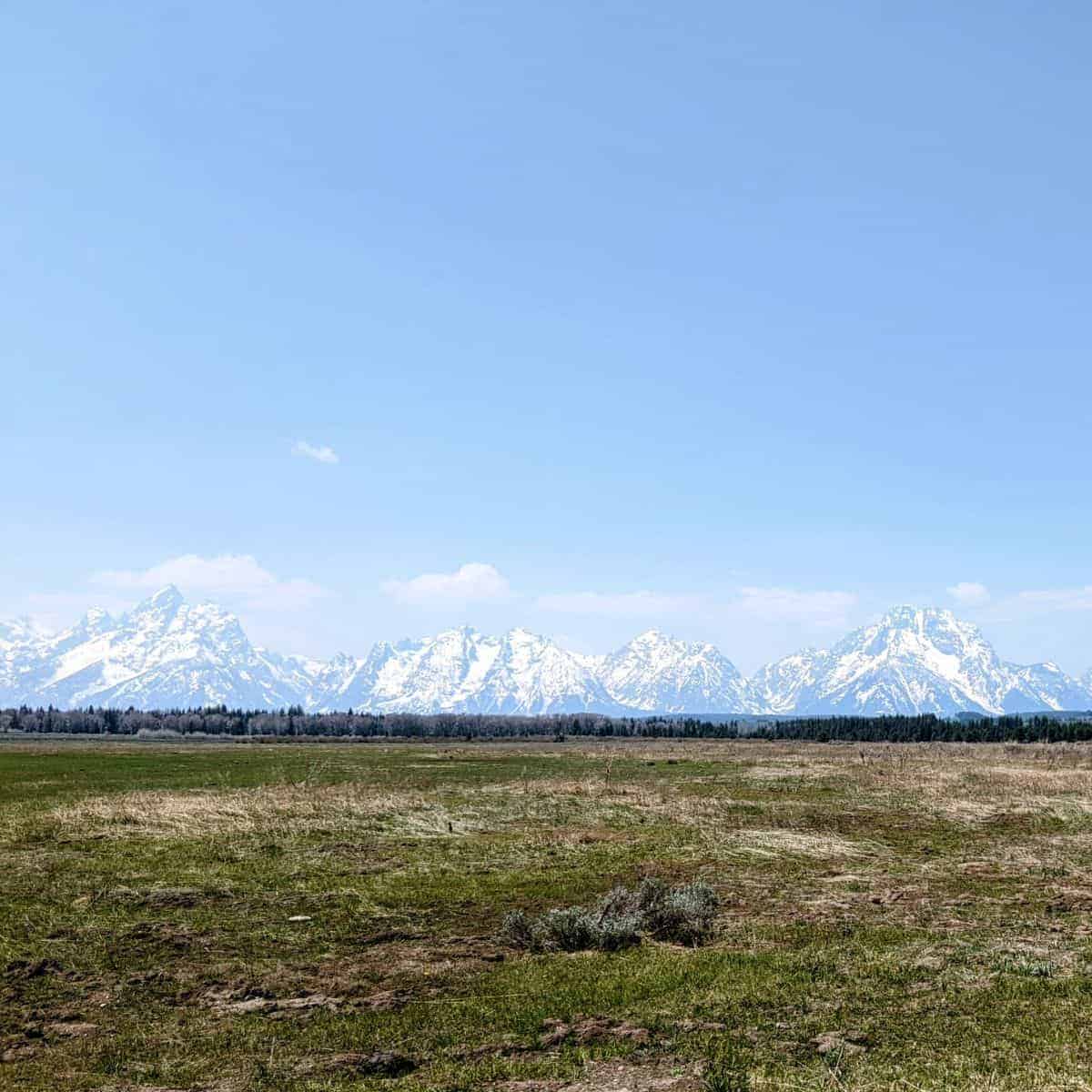 view of the Teton Range across a long expanse of flat land