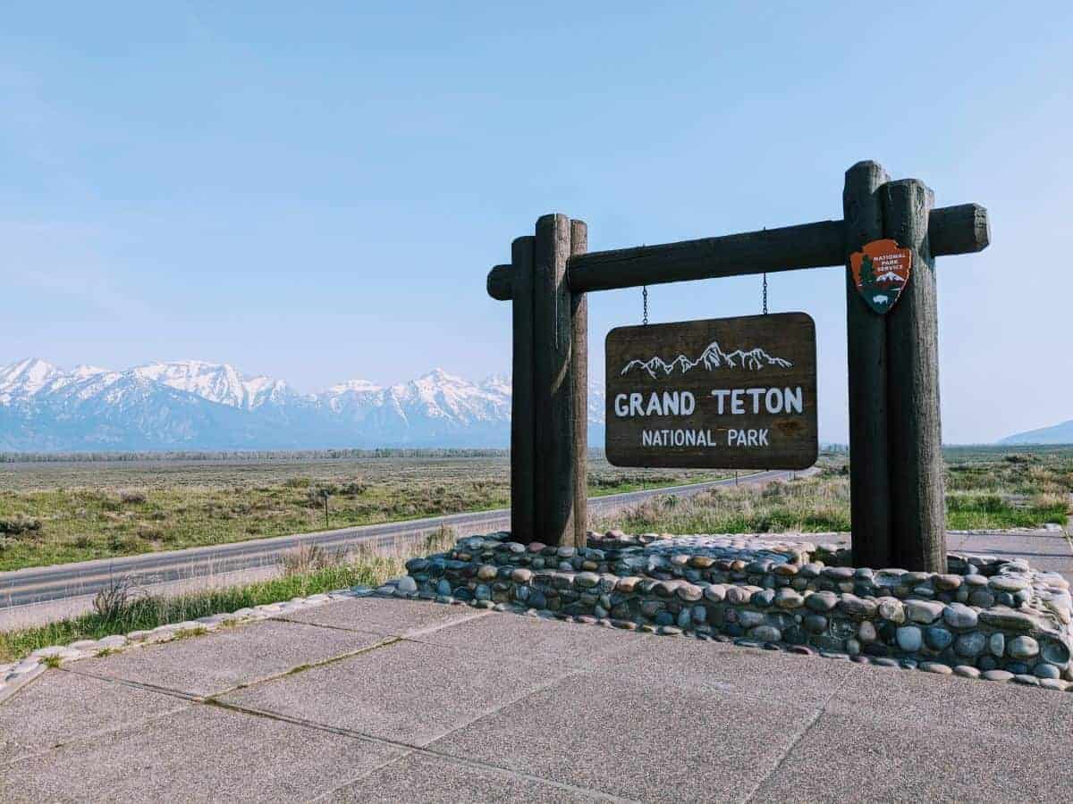 wood sign for Grand Teton National Park with the Teton Range in the background