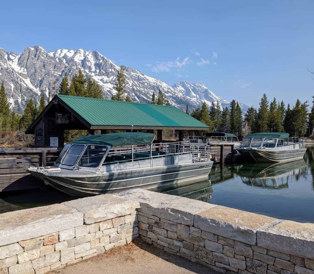 three boats with green canopies and windscreens tied up at a boat dock on a lake