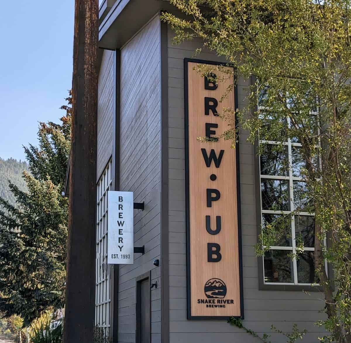 vertical sign on the side of a grey building. The sign says Brew Pub, Snake River Brewing.