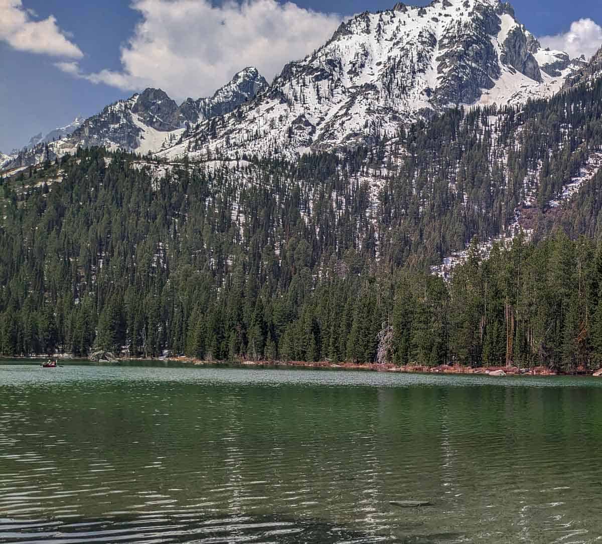 snow-covered mountain right on the edge of a clear green mountain lake