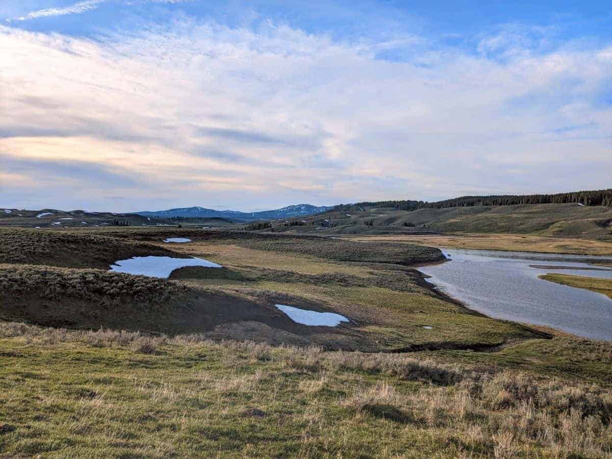 Rolling valley grassland with patches of snow.