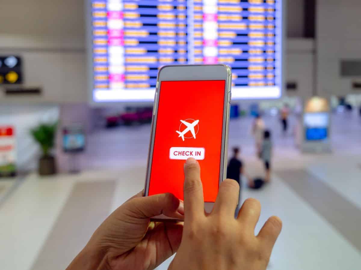 Hands holding a phone tapping on a generic app to check in for a flight.