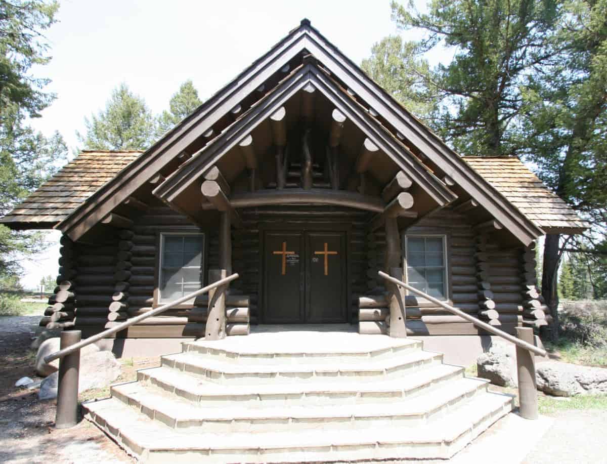 Log cabin church with wooden stairs and cross symbols on doors.